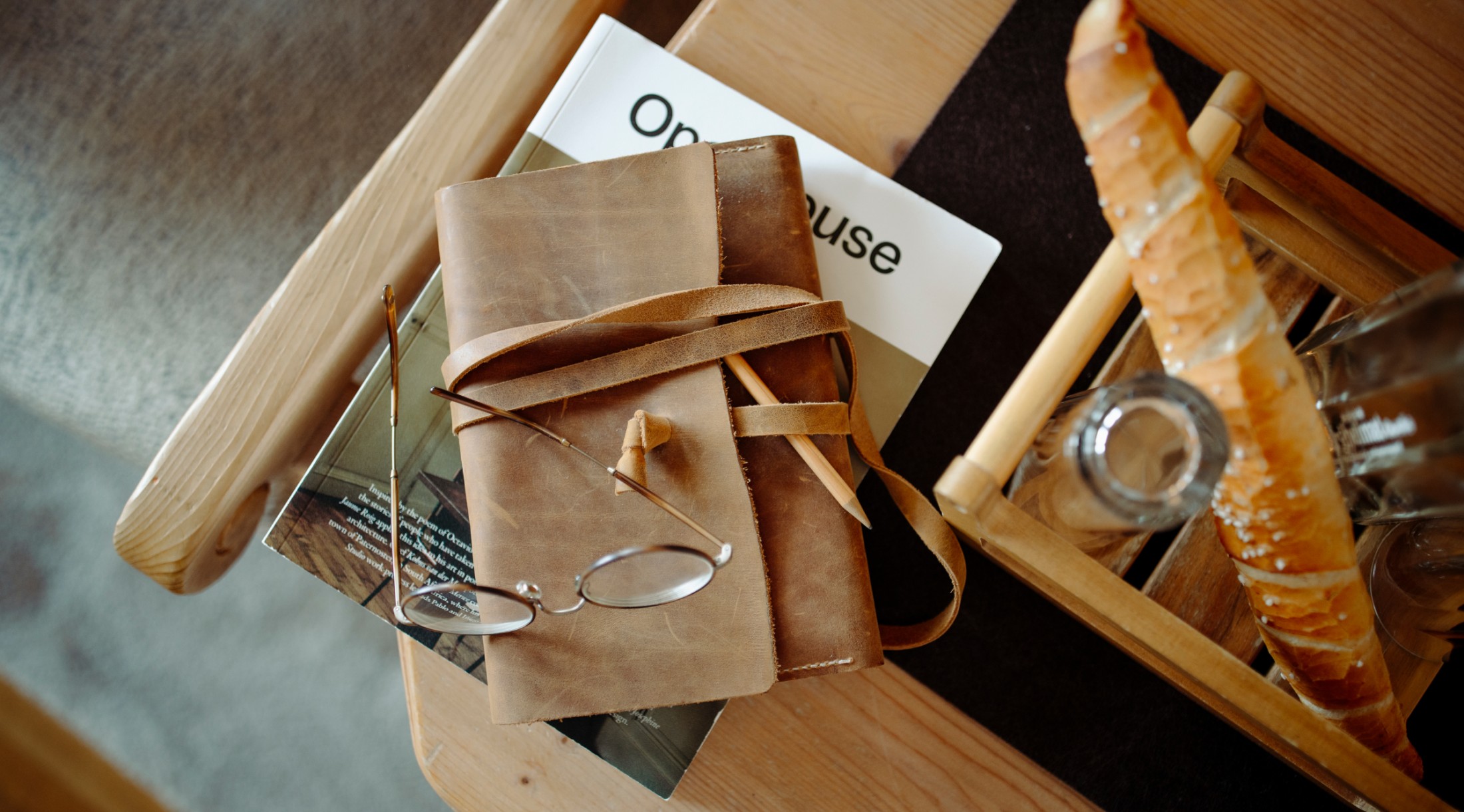 Notizbuch, Brille und Baguette auf einem gemütlichen Frühstückstisch in der Bergheimat